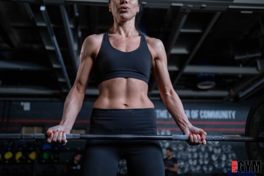 Woman in fitness centre holding strength training bar